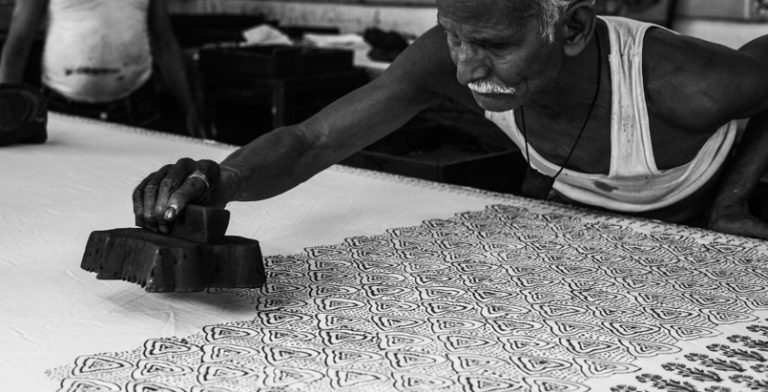 An old man decorating white fabric with block printing technique.
